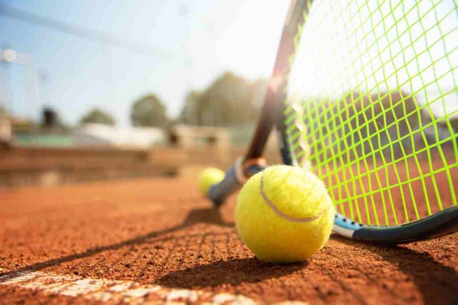 Racchetta e pallina da tennis sul campo in terra rossa
