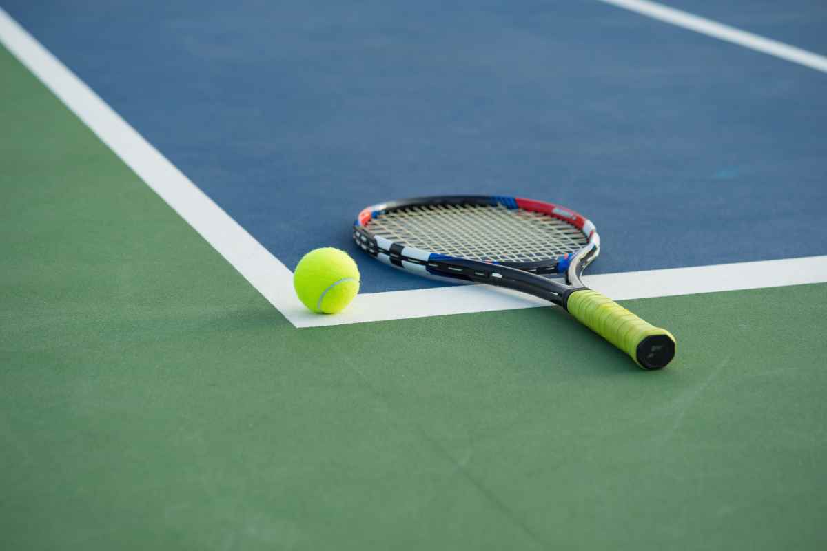 Racchetta e pallina da tennis sul campo in cemento
